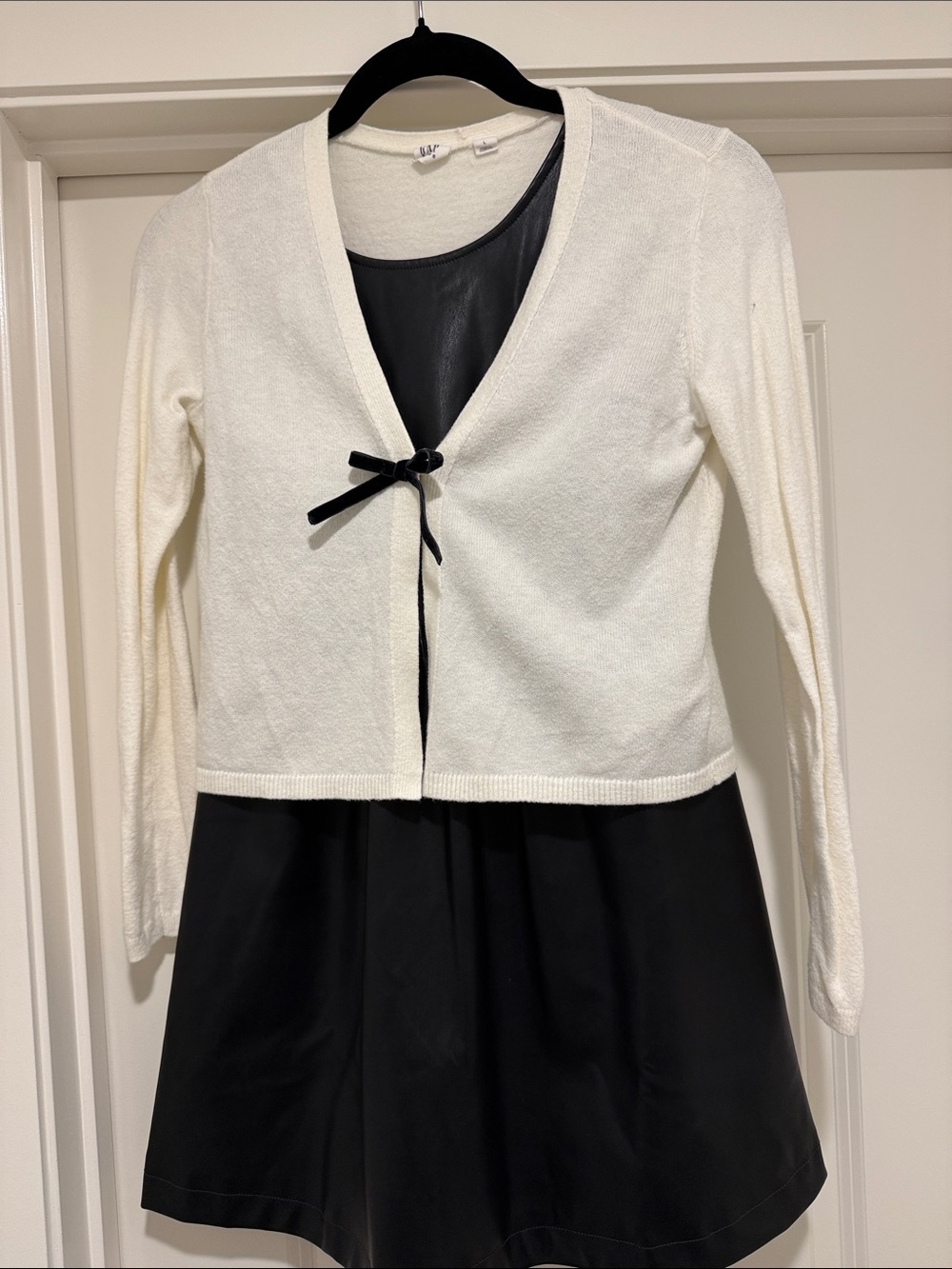 White Cropped Cardigan with Black Bow Over Black Faux Leather Dress